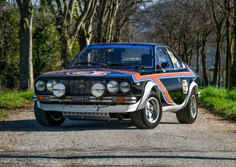 : Vista anteriore di tre quarti della Lancia Beta Coupé Gruppo 4 in livrea nera e arancione.