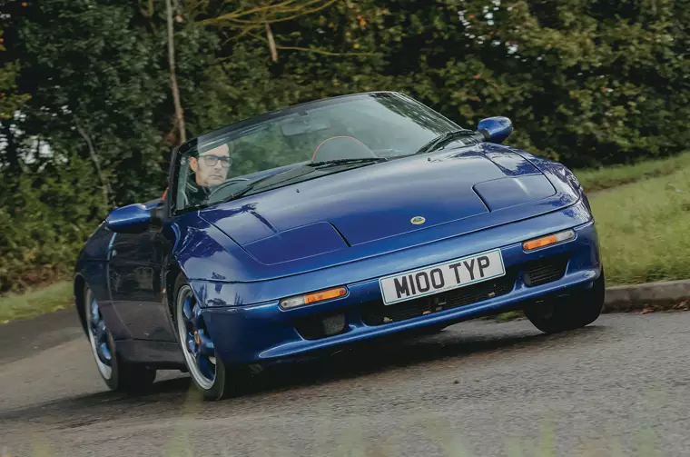 Lotus Elan S2 di colore blu in fase di curva dinamica guidata da un pilota su strada di campagna.